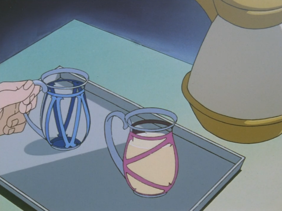A hand picks up a blue glass mug from a tray beside a second mug with pink banding, both filled with the creamy pale drink Miki made, next to a cream-coloured pitcher.