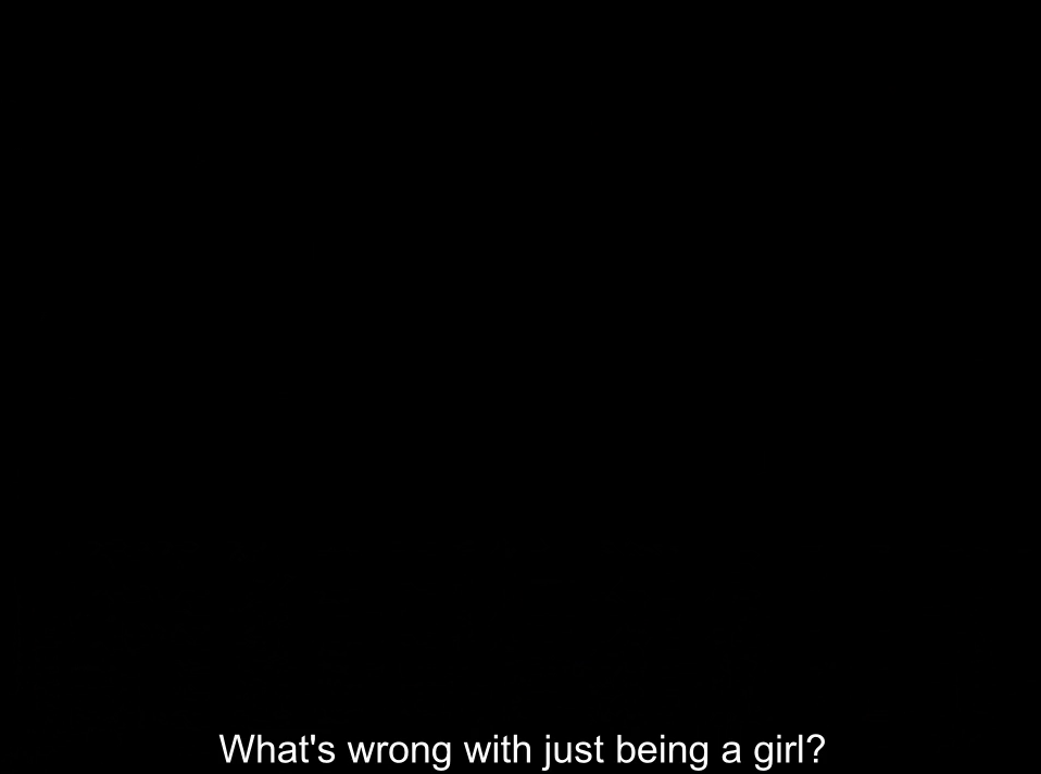 A completely black frame. The subtitle reads “What’s wrong with just being a girl?”